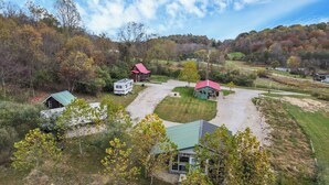 A rural property with a main house, a smaller cabin, and a mobile home. There are trees and a dirt path connecting the buildings. - Cozy Cabin (New Lexington)