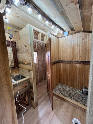 Un interior de madera con un lavabo integrado, un banco y una puerta que da a otra habitación.