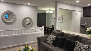 Un salon moderne avec un canapé gris, des coussins décoratifs et une petite table sur laquelle est posé un vase de fleurs.