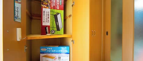 A wooden cabinet with two shelves, one containing a box labeled 'BBQ' and the other a box labeled 'Aluminum Folding Table.'