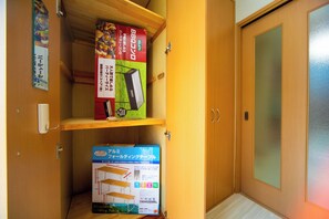 Un meuble en bois doté de deux étagères : l’une contient une boîte étiquetée « BBQ » et l’autre, une boîte étiquetée « Table pliante en aluminium ».
