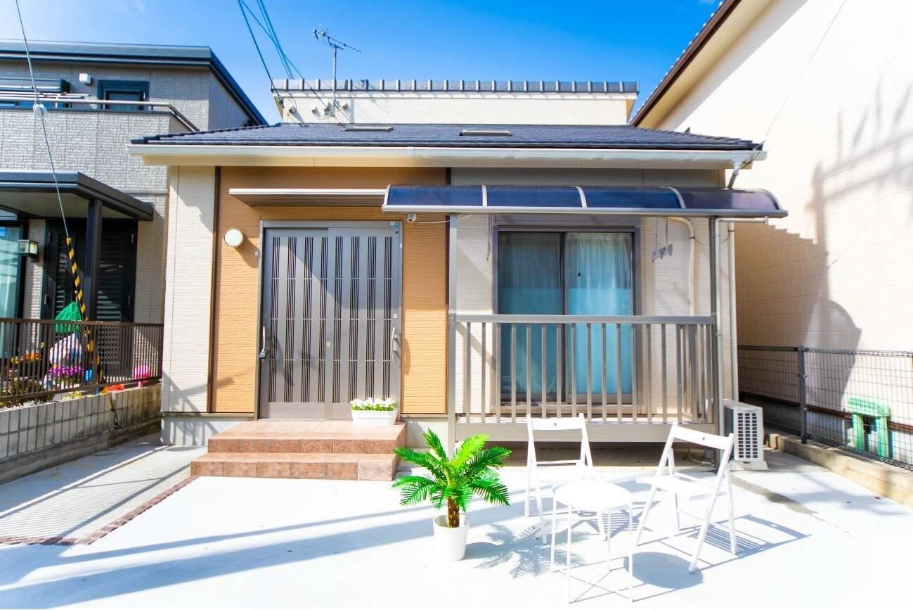 A residential building with a balcony, a potted plant, and a small outdoor seating area.
