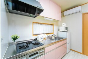 Une cuisine de taille réduite équipée d’une cuisinière à gaz, d’un four à micro-ondes et d’un petit réfrigérateur.