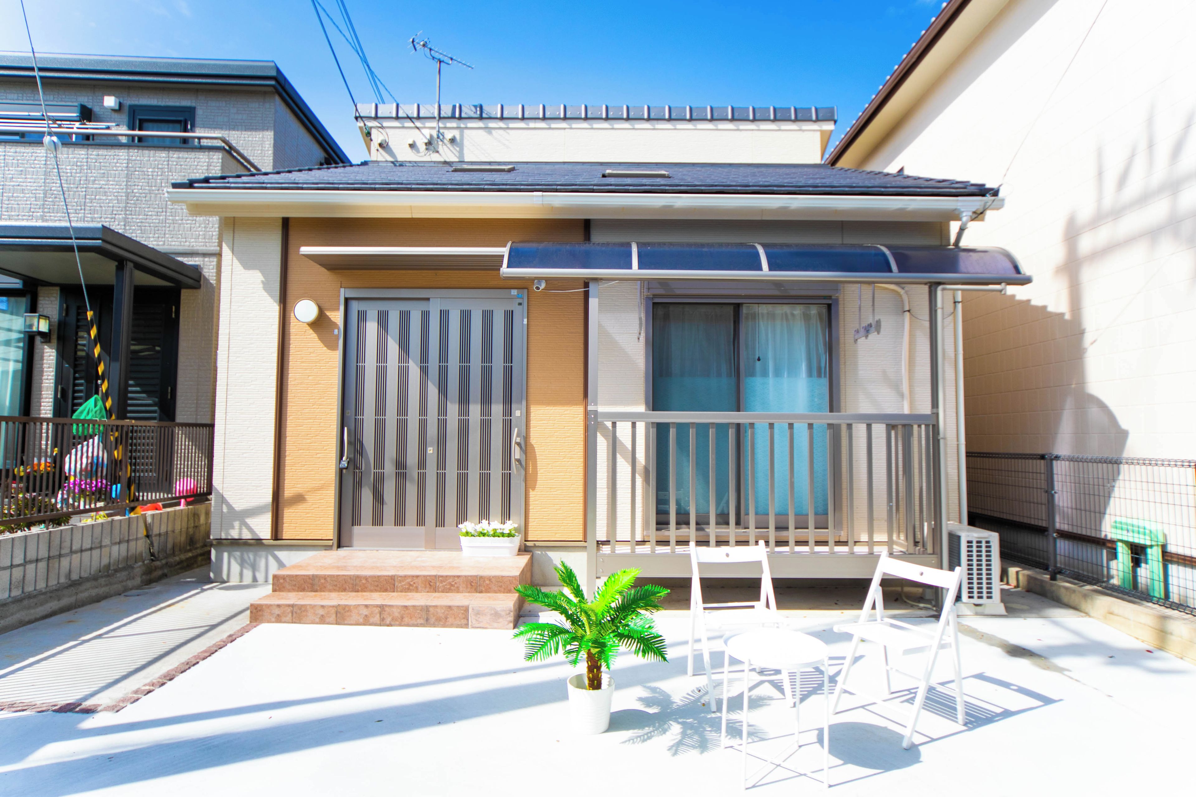 A residential building with a balcony, a door with a vertical metal grille, and a small potted plant.