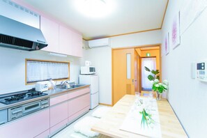 Una cocina compacta con armarios rosados, un horno, un microondas y un refrigerador.