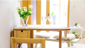 A wooden dining table with two chairs, a vase with white flowers, and two empty wine glasses. - Awaji Central Inn Kuruma713 (Awaji)