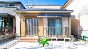 A residential building with a balcony, a small garden, and a white chair. - Awaji Central Inn Kuruma713 (Awaji)