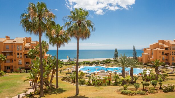 Ein Resort mit Pool, Palmen und Meerblick.