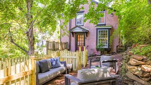 A cozy outdoor seating area with a wooden fence, a stone wall, and a building with a window and door. - John Quigley House Downtown New Hope (New Hope)