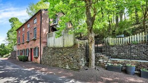 A brick building with a stone wall, a wooden fence, and a tree in front. - John Quigley House Downtown New Hope (New Hope)