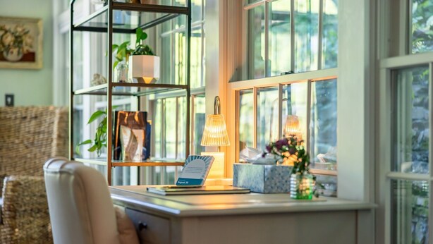 A well-lit room with a desk, a chair, a bookshelf, and a window with a view of greenery. - John Quigley House Downtown New Hope (New Hope)