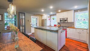 A modern kitchen with white cabinets, a stainless steel microwave, and a wooden island. - John Quigley House Downtown New Hope (New Hope)