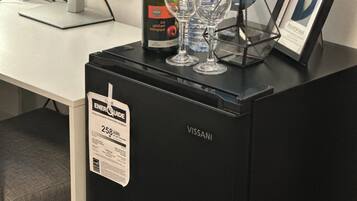 Ein schwarzer VISSANI-Kühlschrank mit Aufkleber zur Angabe des Energieverbrauchs von 258 kWh. Darauf befinden sich eine Weinflasche, zwei Gläser und ein gerahmtes Bild.