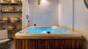 Een moderne badkamer met een houten wastafel, een witte badkuip met blauwe verlichting, en planken met manden en planten.