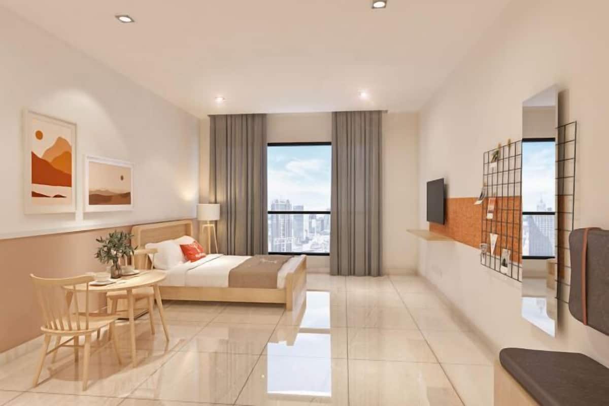 Ett modernt hotellrum med en säng, ett skrivbord, en stol, en TV och ett stort fönster med gardiner.