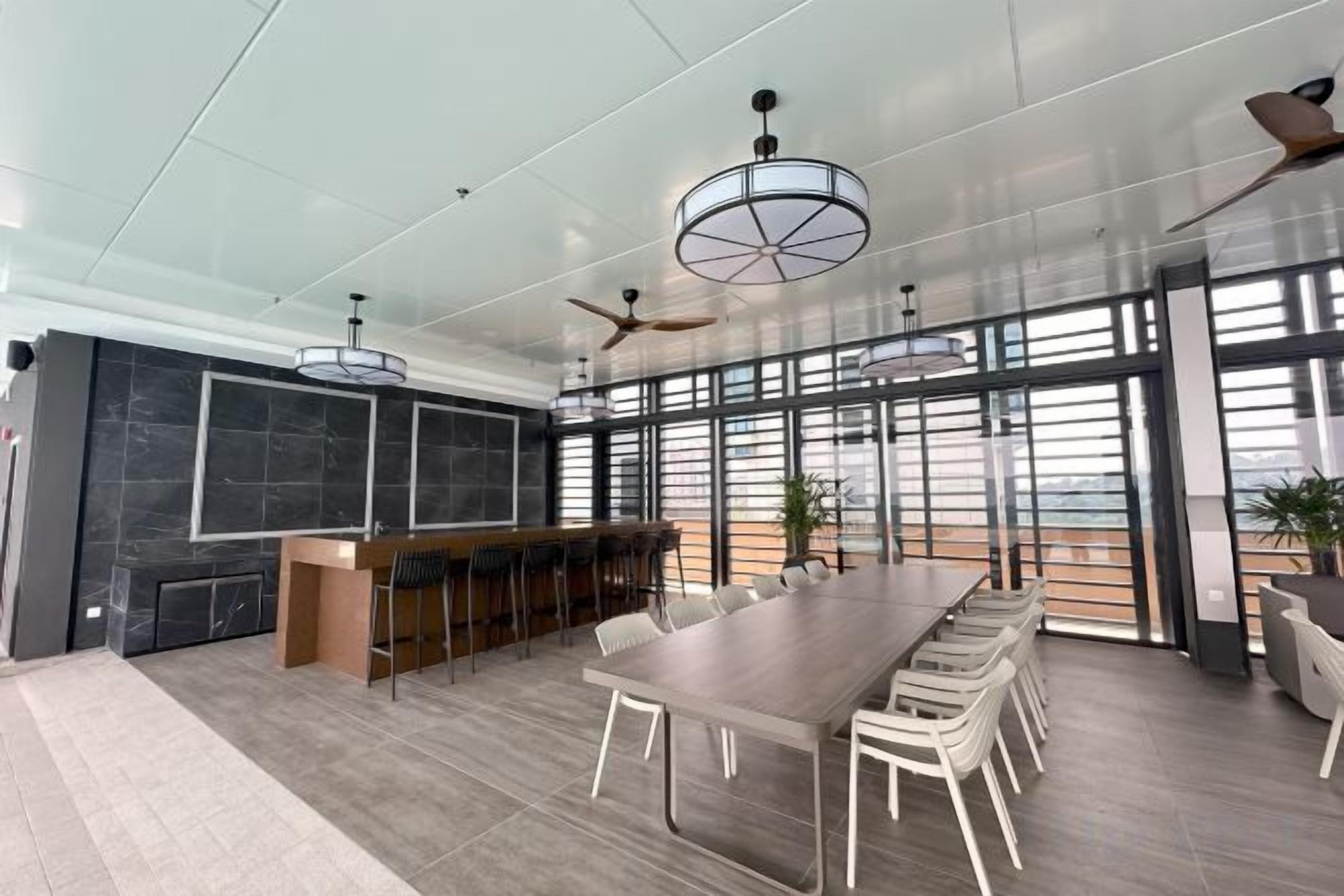 A modern conference room with a long table, chairs, a bar area, and large windows offering a view.