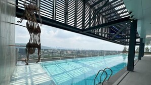 An indoor swimming pool with a view of a cityscape, a metal sculpture, and a glass ceiling structure. - Mossaz Suites by MyKey (Petaling Jaya)