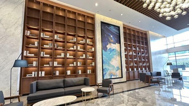 A modern lobby with a large bookshelf, a sofa, and a coffee table. - Mossaz Suites by MyKey (Petaling Jaya)