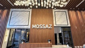 A reception area with a wooden panel wall and a marble floor, featuring the name 'MOSSAZ' prominently displayed. - Mossaz Suites by MyKey (Petaling Jaya)