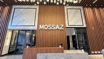 A reception area with a wooden panel wall, a marble-framed entrance, and a modern chandelier.