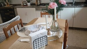 A dining table with a placemat, a candle, a vase with flowers, and a metal candle holder. - Casa SantaMaria (Lousame)