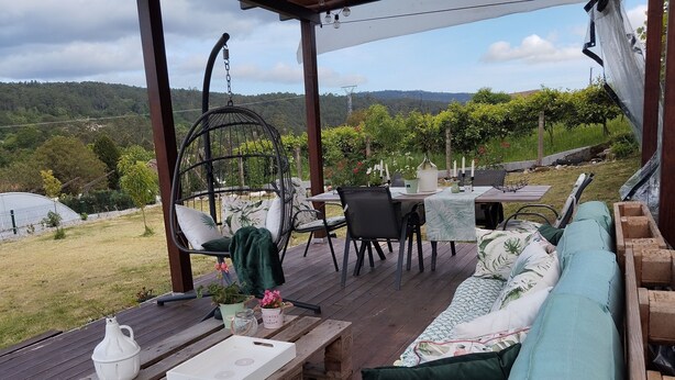 A wooden deck with a hanging chair, a table, and a sofa. - Casa SantaMaria (Lousame)