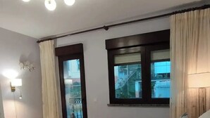 A hotel room with a bed, a bedside table, a lamp, a window with curtains, and a view of the outside. - Casa SantaMaria (Lousame)