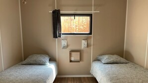 A room with two beds, a window with curtains, a wall-mounted light, and a small shelf. - CHALET WITH EXCEPTIONAL SEA VIEW (Saint-Raphaël)
