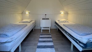 A small, triangular attic bedroom with two single beds, a small table, and a skylight. - Holiday Home for 2 in Stenungsund (Stenungsund)