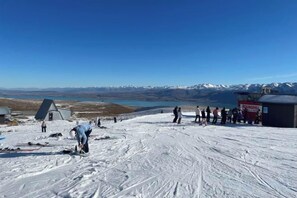 Un paisaje nevado con cielo despejado, un grupo de personas y un edificio con la leyenda 'ROUNDHILL'.