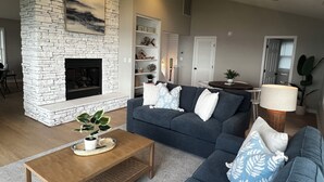 A living room with a stone fireplace, a dark blue sofa, a wooden coffee table, and a lamp.