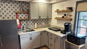 A kitchen with a refrigerator, sink, microwave, coffee maker, and a window with a view. - Charming, quiet cottage in brilliant Fallbrook with AC, WiFi, private, Smart TV. (Fallbrook)