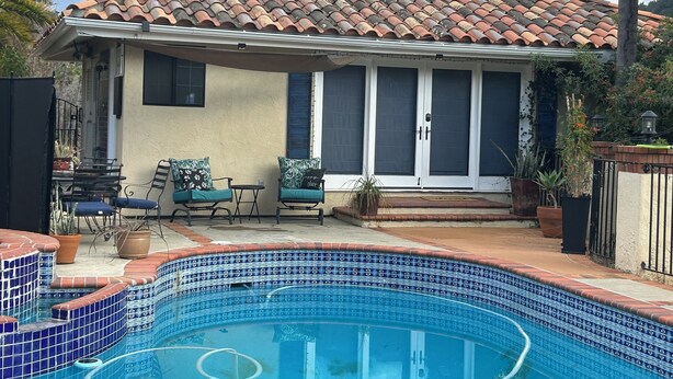 A house with a swimming pool, a patio with chairs and a table, and a covered area with a door. - Charming, quiet cottage in brilliant Fallbrook with AC, WiFi, private, Smart TV. (Fallbrook)