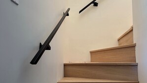 A staircase with wooden steps and black handrails. - Chalet au toit vert (Sainte-Marguerite-du-Lac-Masson)