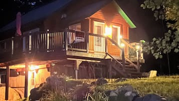 A wooden cabin with a porch and a staircase leading to the entrance.