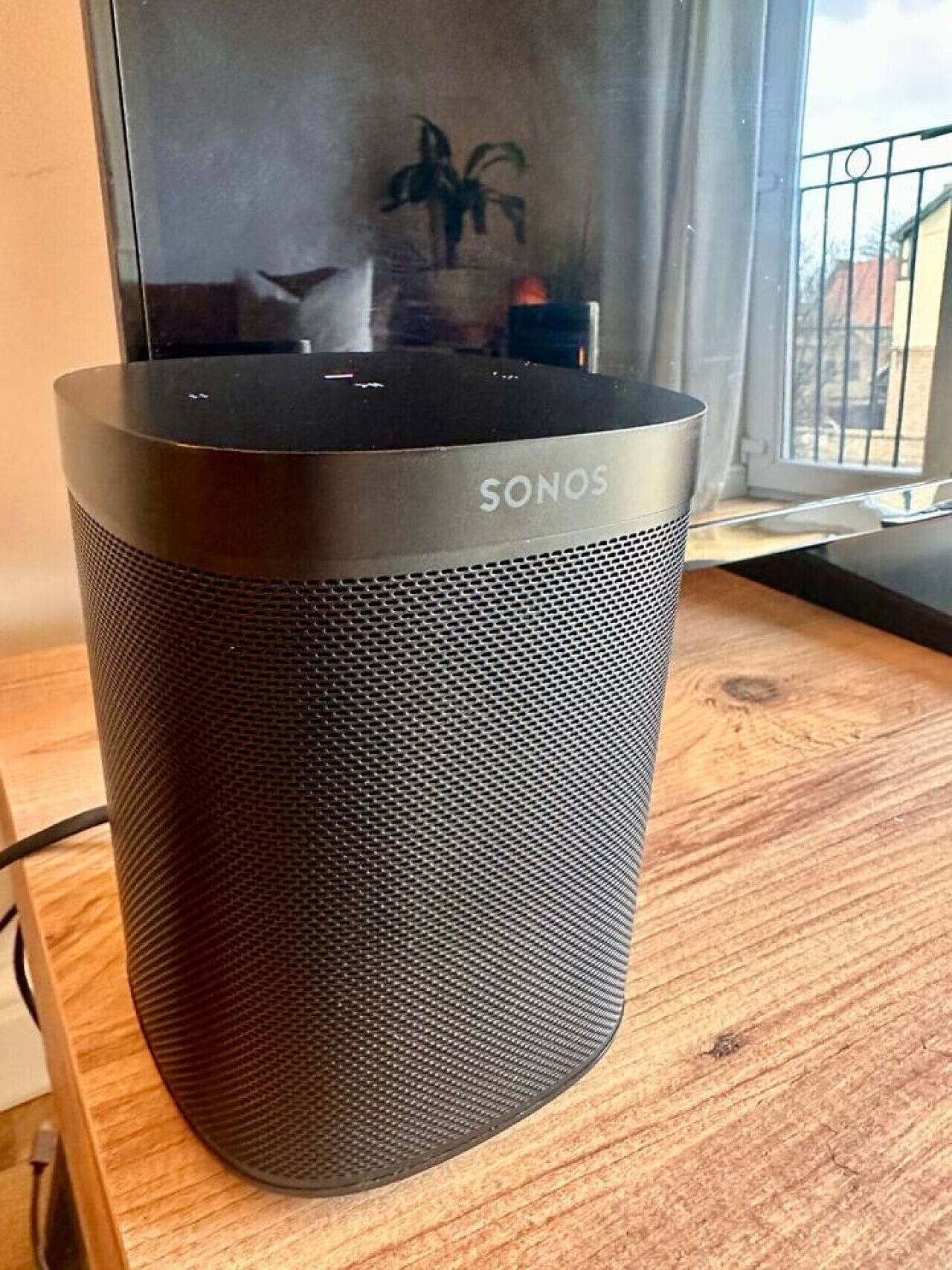 Ein schwarzer SONOS-Lautsprecher auf einer Holztischplatte.