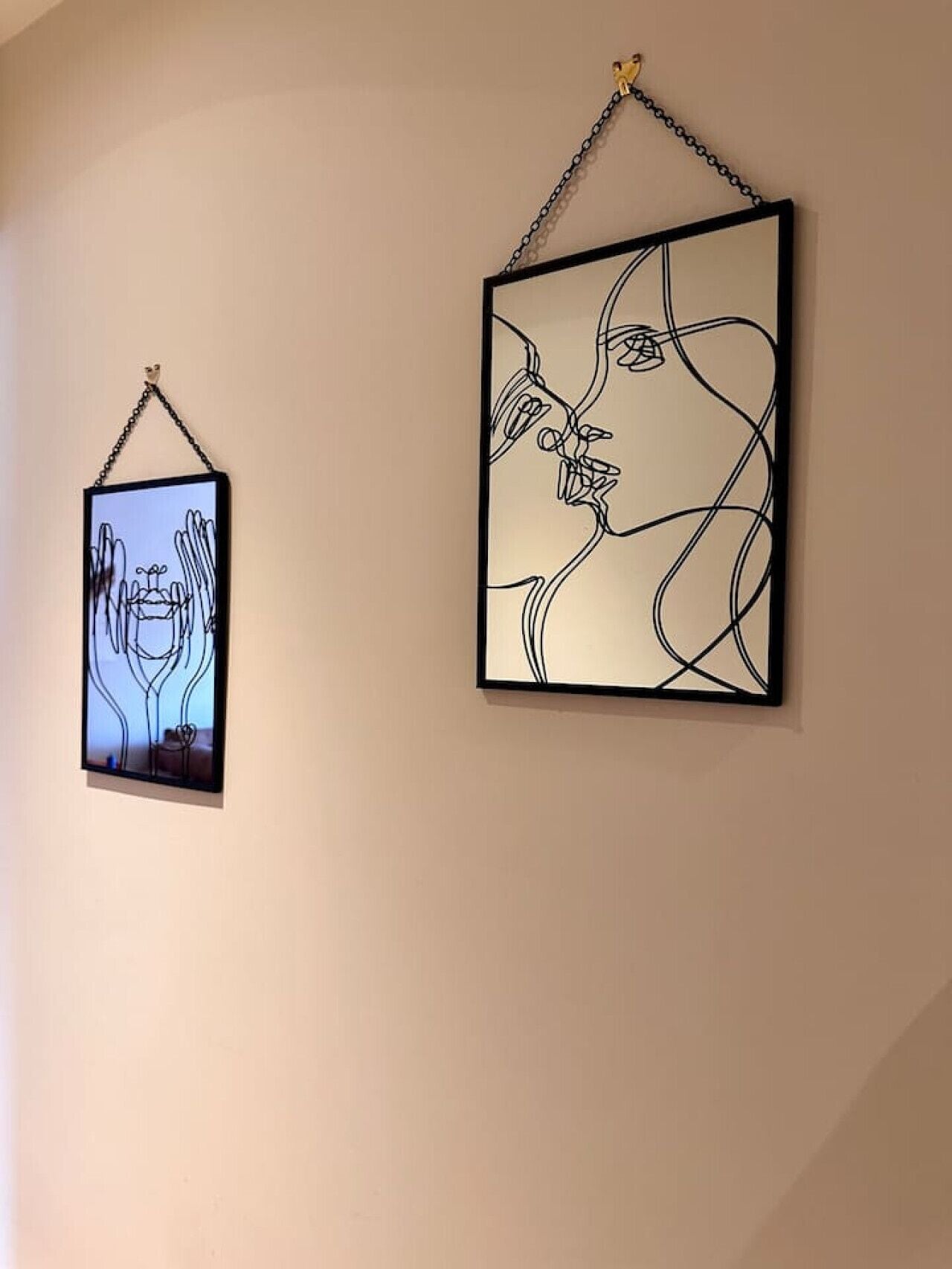 Two framed artworks hanging on a plain wall.