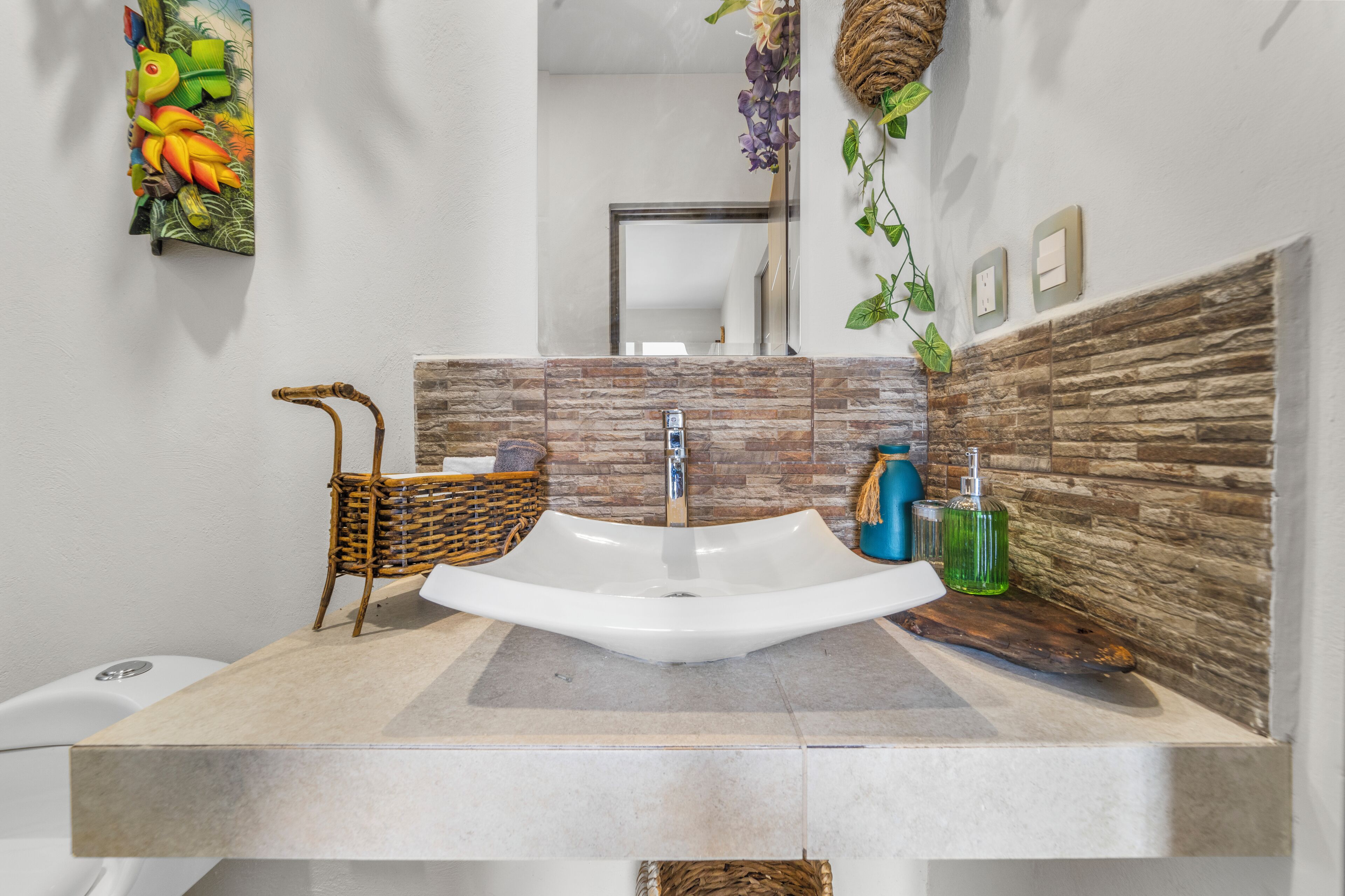 A modern bathroom with a large sink, a mirror, and a decorative wall.