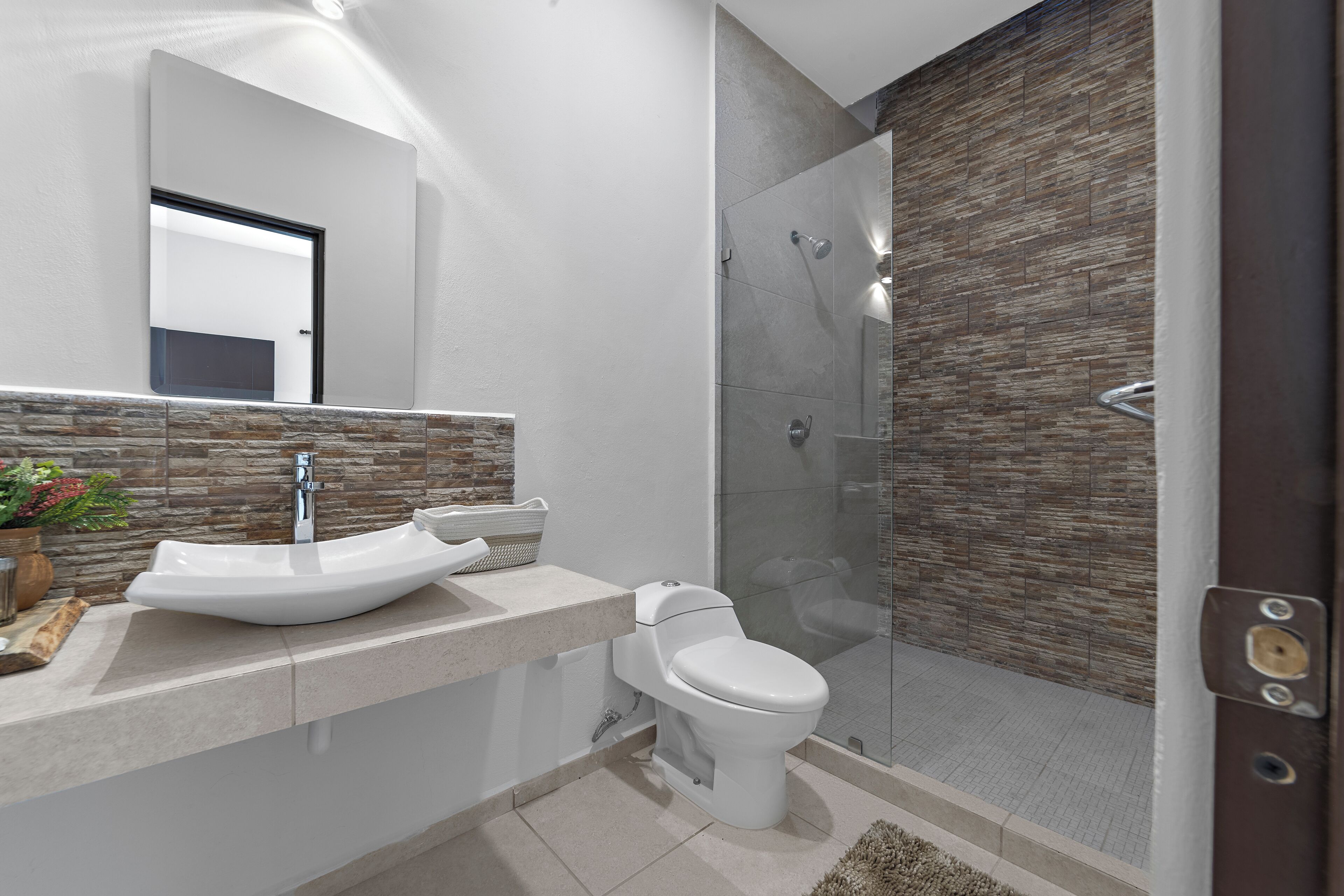 A modern bathroom with a large sink, toilet, and glass shower enclosure.