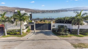 A gated entrance to a property with a view of a lake and hills in the background. - Casa Familiar Alberca vista al lago 4 RC (Jojutla)