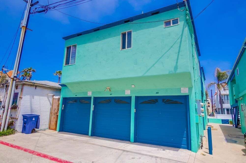 A two-story building with a teal exterior and three garage doors.