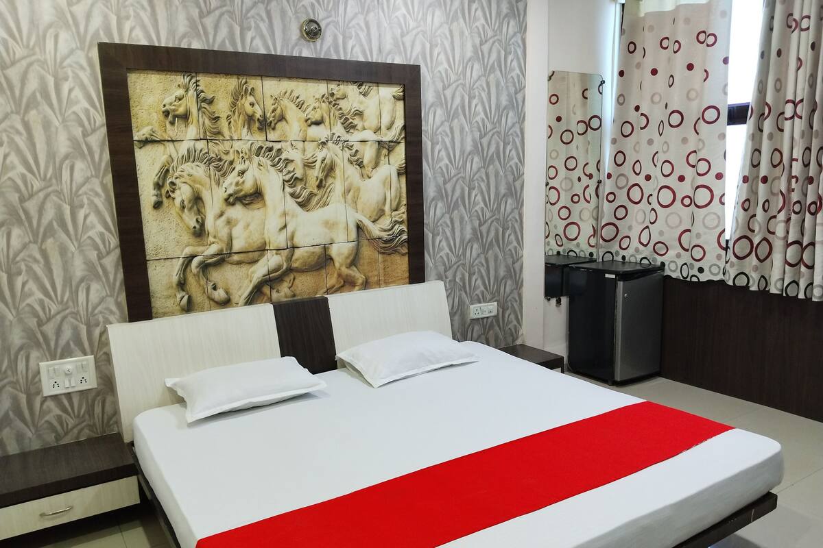 A hotel room with a large bed, a headboard with a horse mural, a small desk, and a mirror.