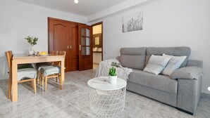 A living room with a grey sofa, a round coffee table, and a dining table with chairs. - ALTAMIRA Apartment (La Pineda)
