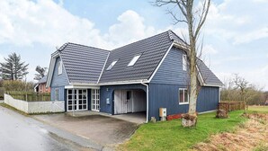 A two-story house with a sloped roof, a garage, and a fenced yard. - 6 Person Holiday Home in Snedsted (Snedsted)