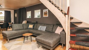 A modern living room with a wooden staircase, a sectional sofa, and a dining area. - 6 Person Holiday Home in Snedsted (Snedsted)