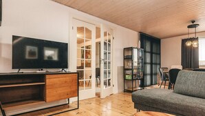 A modern living room with a flat-screen TV, wooden flooring, a grey sofa, and a small wooden coffee table. - 6 Person Holiday Home in Snedsted (Snedsted)