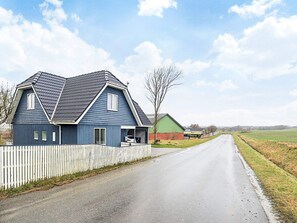 Eine ländliche Straße mit einem blauen Haus und einem grünen Schuppen.