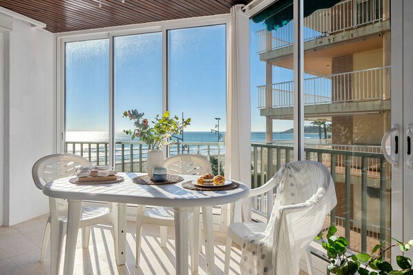 A balcony with a table set for two, overlooking a beach and a building with multiple balconies. - BELL RACO Apartments (La Pineda)