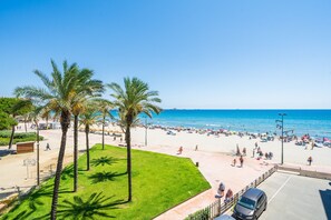 A beach with palm trees, a parking area, and a clear blue sky. - BELL RACO Apartments (La Pineda)