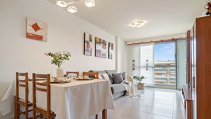 A dining area with a table set for two, a sofa, and a balcony with a view. - MALDIVAS III Complex (La Pineda)